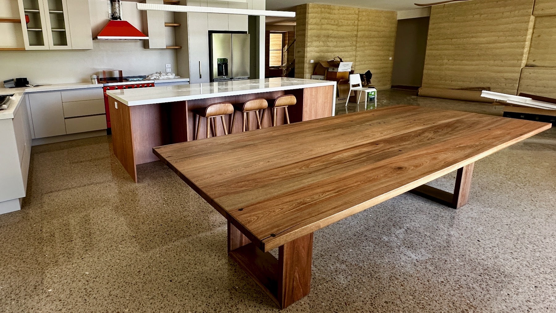 Christian Cole timber dining table set up in the kitchen with stools behind.