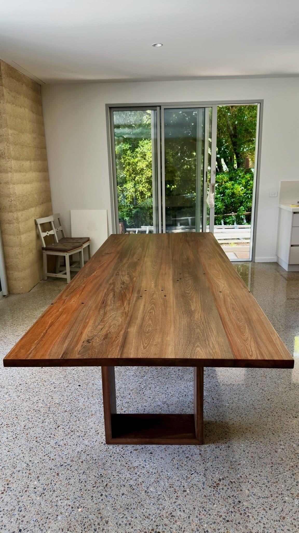 End view of the timber dining table set in a bright interior.