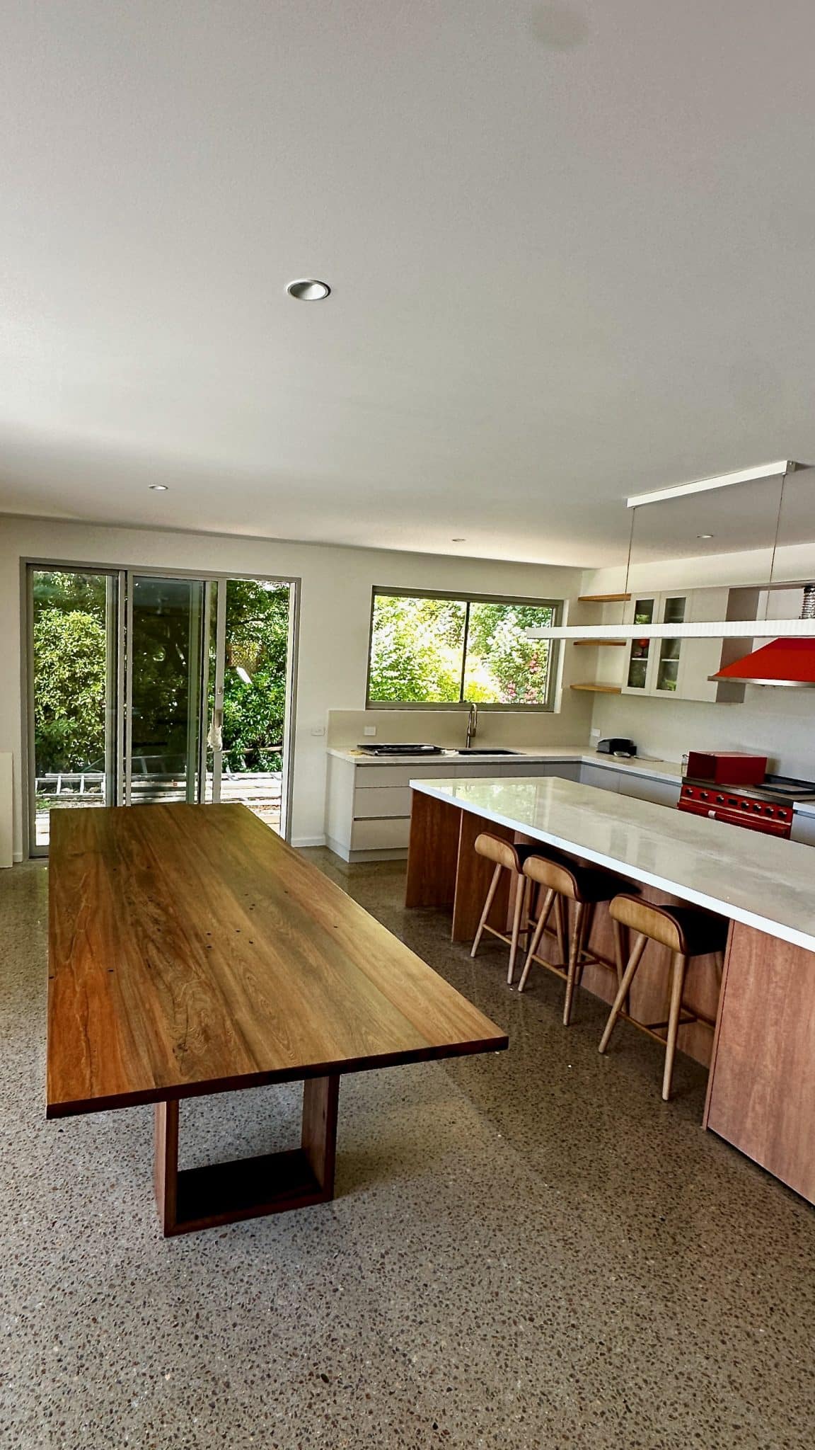 timber dining table in place with kitchen seating and cabinetry behind.