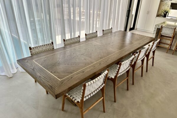 Side angle of a Christian Cole dining table near full-height curtains