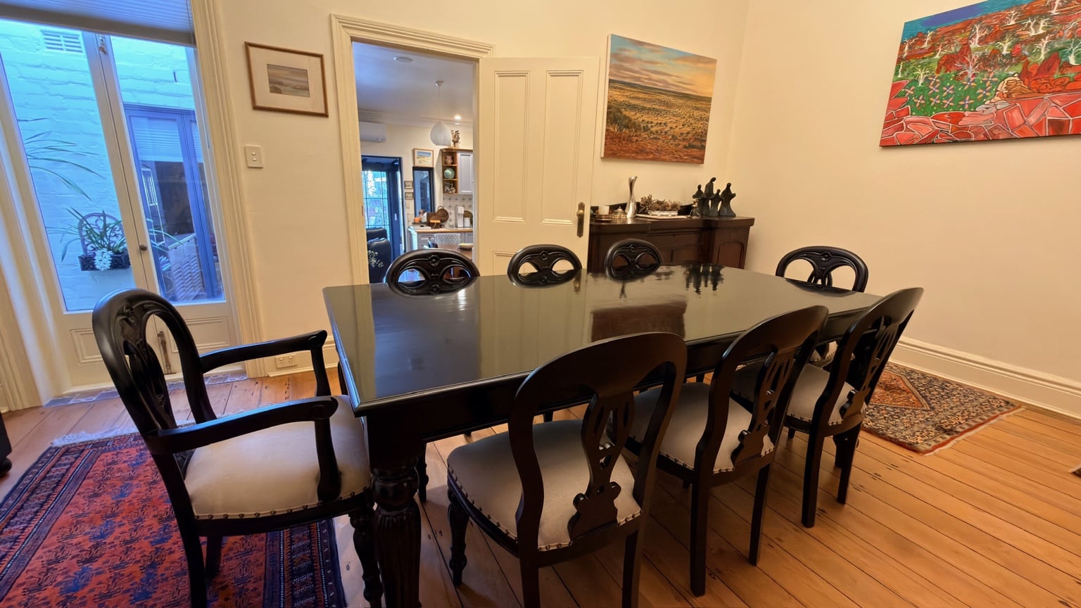 Close view of a dark timber dining table and upholstered chairs after assembly in McMahons Point