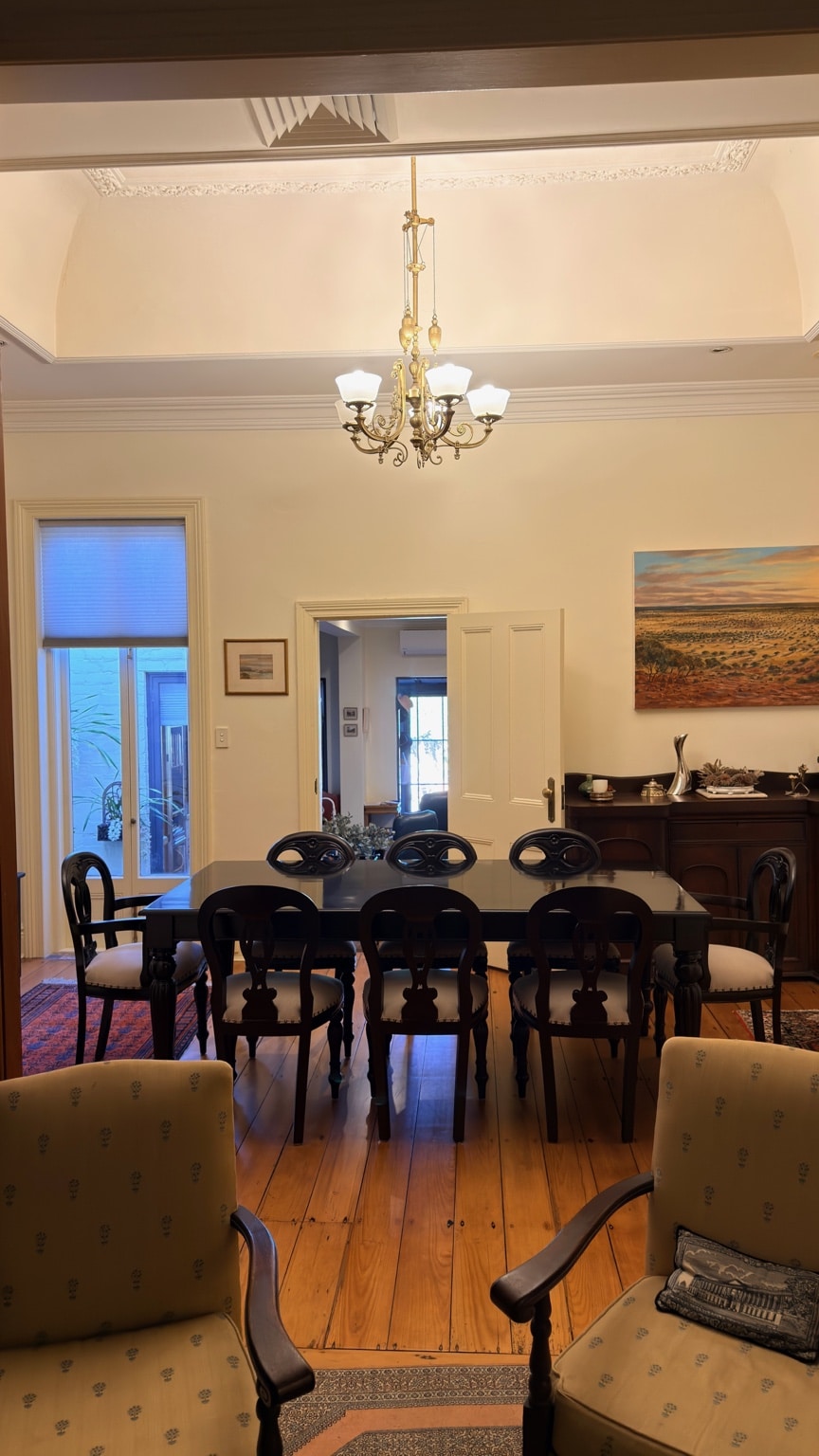 Dining table and eight chairs positioned beneath a chandelier after delivery and assembly