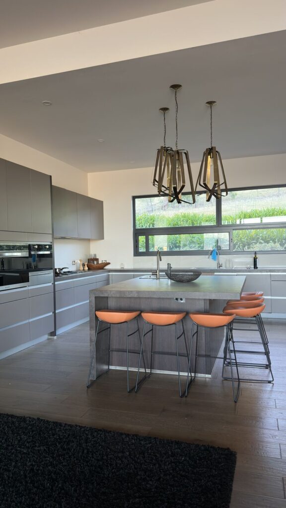 Kitchen island and bar stools shown in the surrounding open-plan room