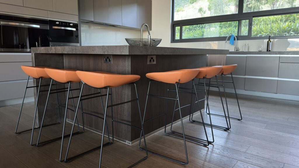 Six tan bar stools arranged around a large kitchen island