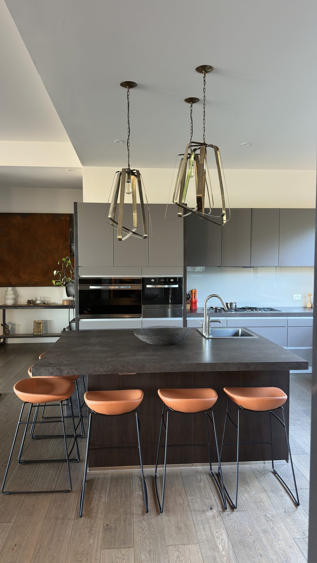 Front view of tan upholstered bar stools beneath pendant lights