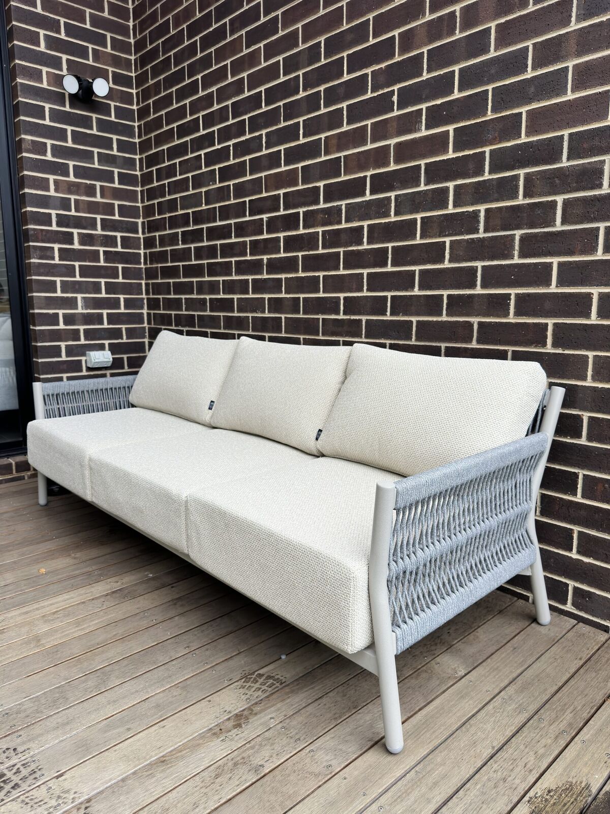 Three-seat teak and rope outdoor sofa carefully positioned after delivery in Doncaster East.