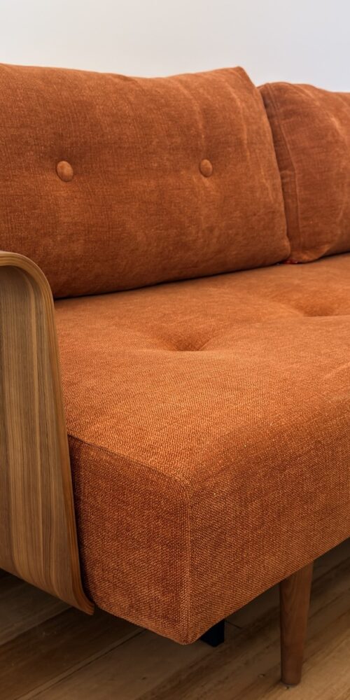Rust-coloured Innovation Living Recast sofa bed with curved timber arms and buttoned cushions, delivered to Coburg by Phil’s Furniture Freighters.