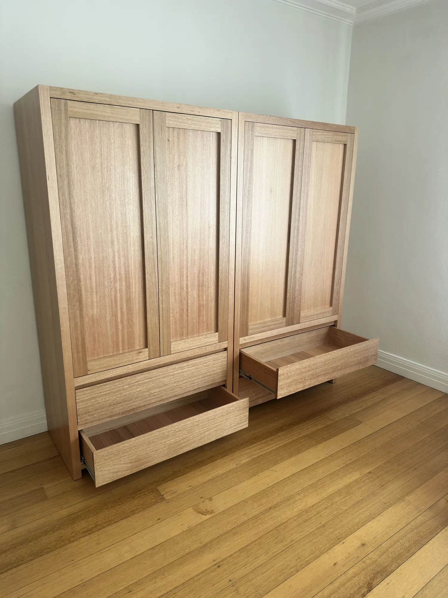 Two timber wardrobes with lower drawers open and upper panelled doors closed.