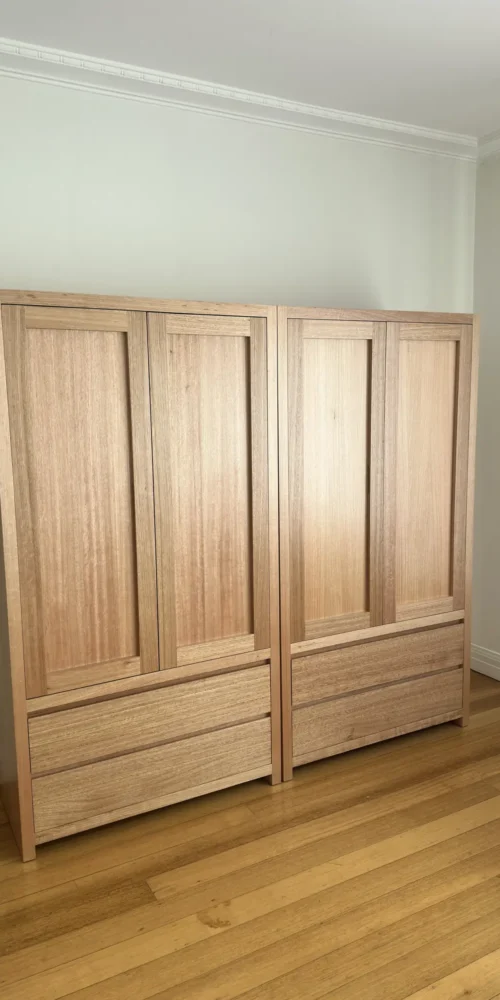 Two timber wardrobes with closed panelled doors and lower drawers in a South Yarra room.