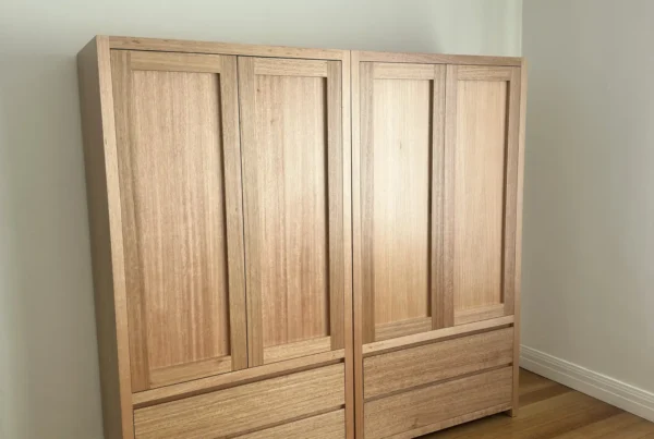 Two timber wardrobes with closed panelled doors and lower drawers in a South Yarra room.